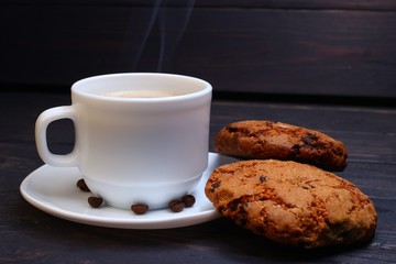 A cup of cappuccino and sweets on a dark wooden background