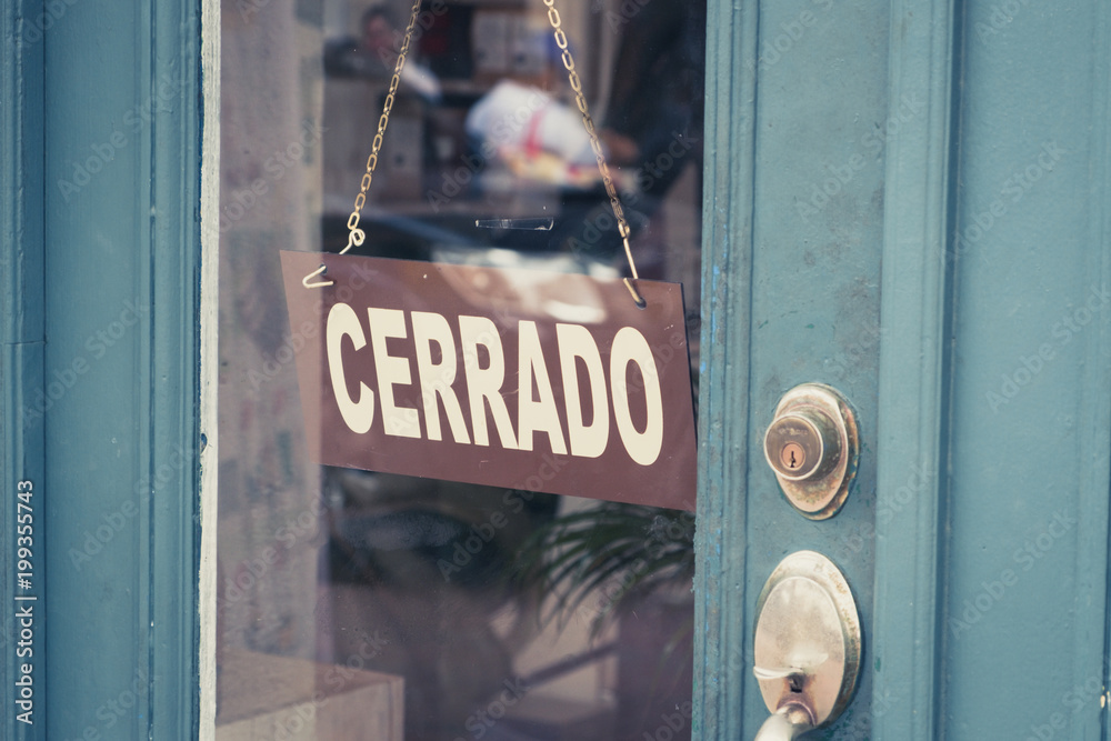 Cerrado (closed) sign on door - spanish word "cerrado" (closed) on shop entrance - - obrazy, fototapety, plakaty 