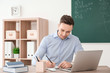 © New Africa - Young male teacher working at table in classroom