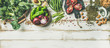 Winter vegetarian, vegan food cooking ingredients. Flat-lay of vegetables, fruit, beans, cereals, kitchen utencil, dried flowers, olive oil over white wooden background, top view, copy space