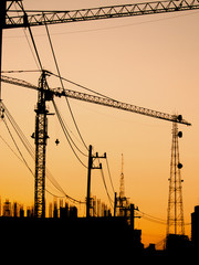  silhouette of building under construction with crane at sunset