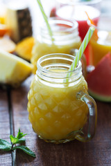 Wall Mural - Fresh pineapple smoothie in a glass and fruits, closeup