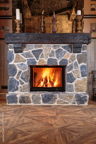 Fotografía blazing fire in the massive fireplace of hewn stone on a beautiful wooden floor