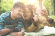 © Mladen - African American couple lying down in meadow and taking self portrait.