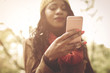 © Mladen - Young African America girl in park using smart phone. Focus is on hand.
