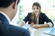 © Natee Meepian - Cropped image of real estate agent assisting client to sign contract paper at desk with house model