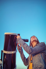 Wall Mural - cute young woman holding astronomical telescope and looking at the sky.