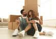 © ASDF - married couple sitting near cardboard boxes in a new apartment
