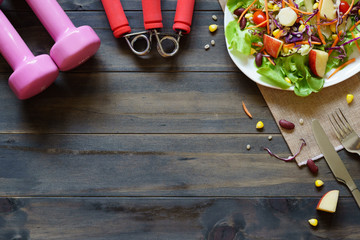 Poster - Healthy lifestyle, Fitness, Fresh healthy salad, diet and active lifestyles Concept, dumbbells, Fresh healthy salad on wood background. Top view with copy space.