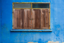 Closed Wooden Windows With Yellow Frame On Old Blue Wall