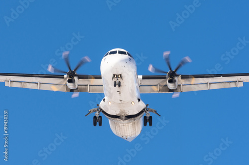 Fotografie, Obraz Turboprop aircraft with propeller engines on its wings before landing on a runway at the airport against a blue sky