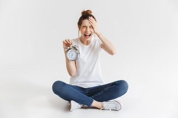 Poster - Portrait of an upset young girl holding alarm clock