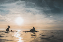 Two Surfer Friends Patiently Wait For A Wave Over The Calm Sea At Sunset. Extreme Water Sports And Outdoor Active Lifestyle. Vintage Filter With Soft Style