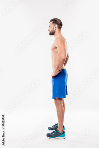 fullbody side view portrait of attractive athletic sportive man holding hands on waist having modern hairstyle and perfect relief body standing on white background buy this stock photo and explore similar fullbody side view portrait of