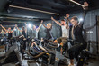 Group of sporty people on exercise bikes celebrating after successful cycling training in gym