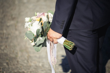 Wall Mural - groom in a tuxedo holding wedding bouquet of roses