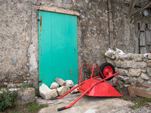 Red Wheelbarrow Lying On The Floor In Front Of A Green Door