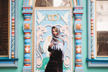 A young beautiful girl in a mink coat and a Russian folk scarf walks around the Izmailovo Kremlin. Moscow, Russia.