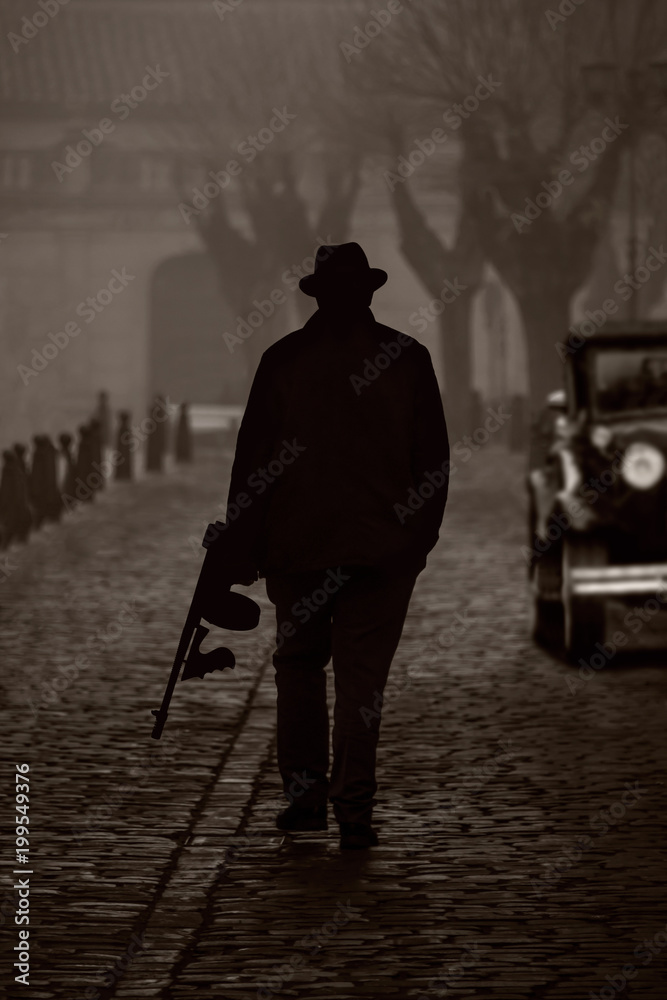Silhouette of a gangster with machine gun, on a street with fog - obrazy, fototapety, plakaty 