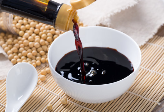Fototapete - Close up of pouring soy sauce in white bowl 