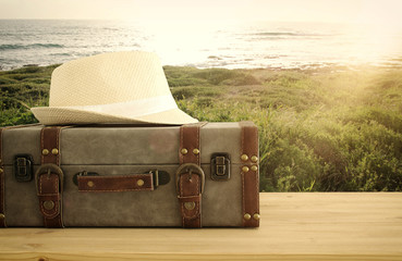 traveler vintage luggage and fedora hat over wooden table. holiday and vacation concept.