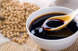 Pouring soy sauce into a white bowl