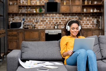 attractive young woman working with laptop and listening music at home