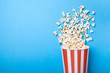 Spilled popcorn and paper bucket in red strip on blue background. Copy space for text