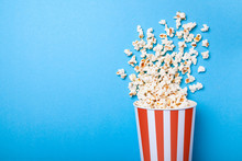 Spilled Popcorn And Paper Bucket In Red Strip On Blue Background. Copy Space For Text