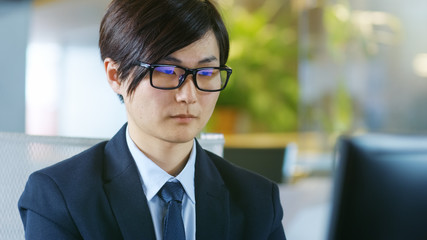 Portrait of the Japanese Businessman Wearing Glasses, Sitting at His Desk and Working On Personal Computer.