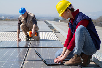 Wall Mural - young engineer girl and an elderly skilled worker fitting a photovoltaic plant