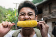 © Full_Chok - Man tourists with backpacks happily eat ripe corn traveling in Asia