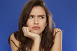 thoughtful young frowning woman on blue background