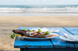 Delicious grilled fish on blue table. Ocean waves on background. Concept of healthy food during vacation
