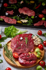 Wall Mural - Still life of raw beef meat with vegetables on wooden plate over white background, top view, selective focus