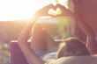 © astrosystem - Girl holding a heart-shape symbol while lying on the couch.