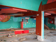 The Interior Of A Derelict Abandoned Discotheque Or Nightclub With Rubble Covered Floor And Wired Hanging From Many Coloured Painted Walls And A Rubbish Covered Stage