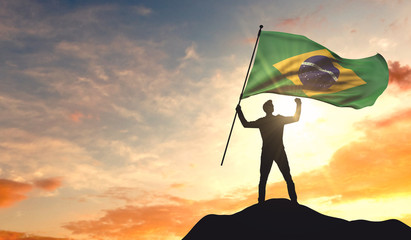 Canvas Print - Brazil flag being waved by a man celebrating success at the top of a mountain. 3D Rendering