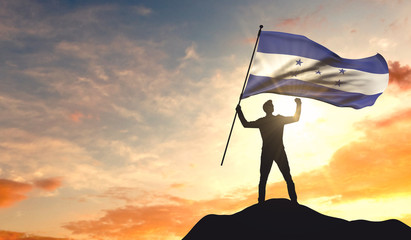 Honduras flag being waved by a man celebrating success at the top of a mountain. 3D Rendering