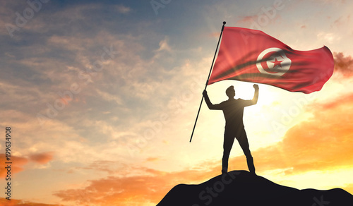 Cuadros en Lienzo Tunisia flag being waved by a man celebrating success at the top of a mountain