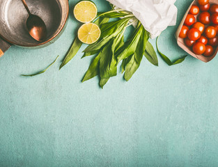 Wall Mural - Wild garlic recipes food background with cooking pot, spoon and ingredients on kitchen table, top view, place for text. Healthy seasonal food and eating concept