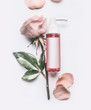 Pink Roses essential cosmetic product bottle with branding mock up and rose flowers and petals on white background, top view