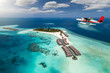 Wasserflugzeug fliegt über Malediven Insel mit türkisem Ozean und blauem Himmel