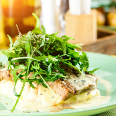 Wall Mural - Mashed potatoes with juicy tasty steak meat in a restaurant in rays of the sun, close-up