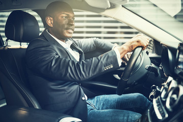 Canvas Print - Smiling African businessman driving his car through city streets