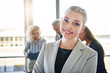 © Flamingo Images - Young businesswoman smiling with colleagues talking in the background