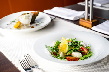 Canvas Print - Tasty vegetarian salad with tomatoes, lettuce leaves, lemon and cheese in a plate