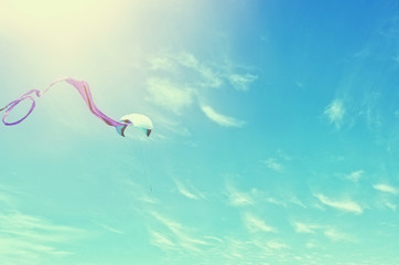 Wall Mural - Colorful kite flying in the blue sky through the clouds