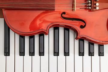 classical violin on white and black piano keys close-up background showing strings