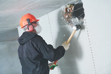 demolition work and rearrangement. worker with sledgehammer destroying wall